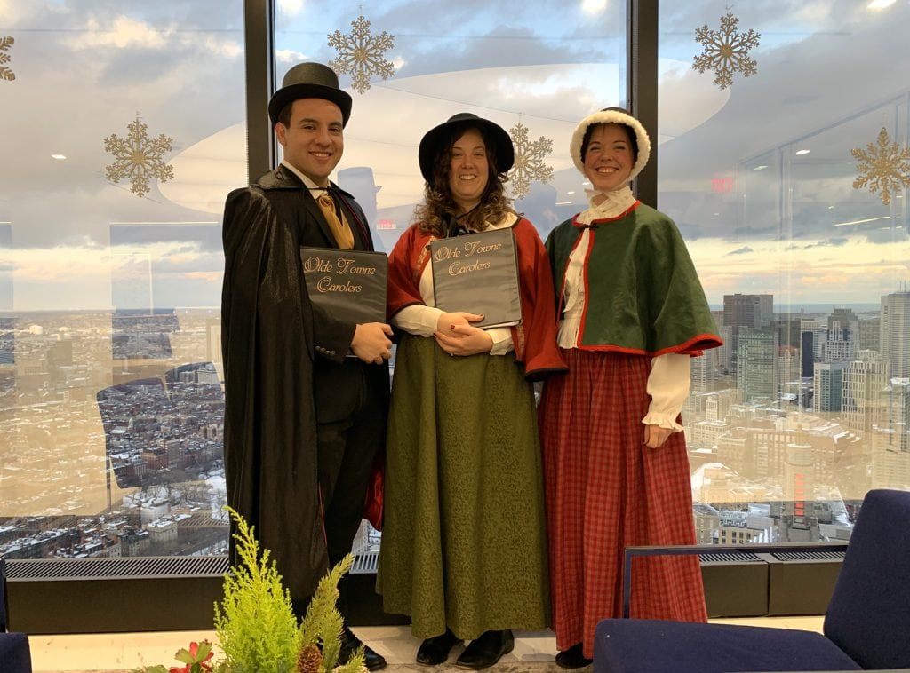 The carolers pause against the Boston skyline during a corporate appearance for the Kirkland & Ellis law firm.