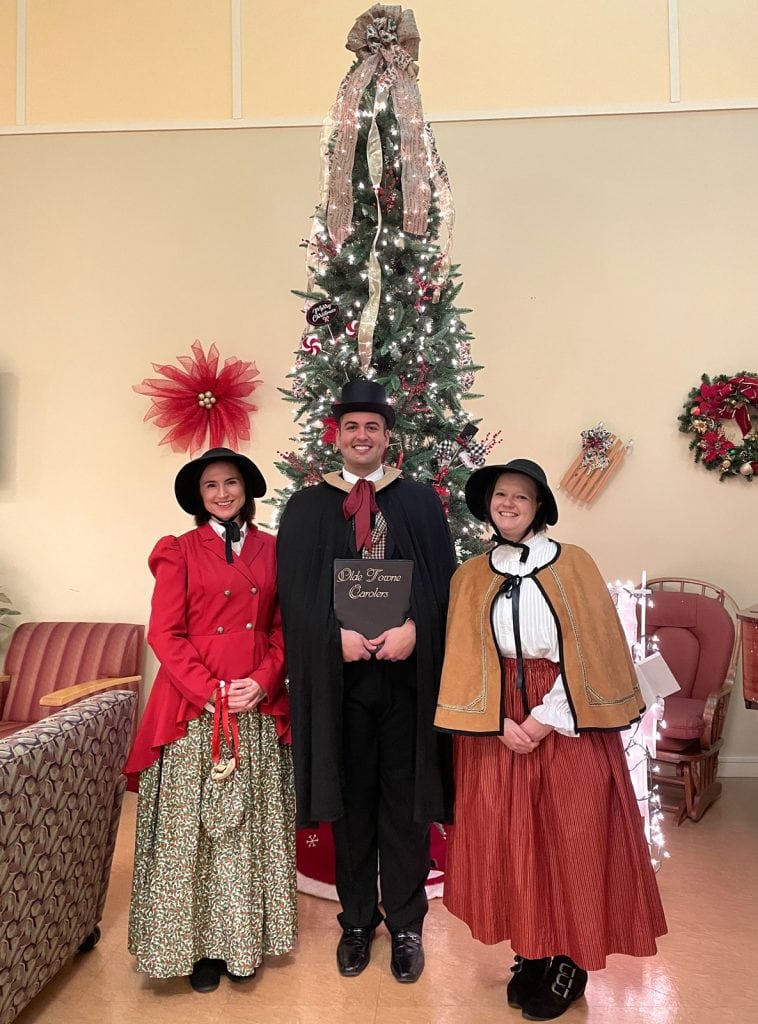 The carolers stop for a pic at a beautiful tree at the Tewksbury Senior Center in Tewksbury, MA.